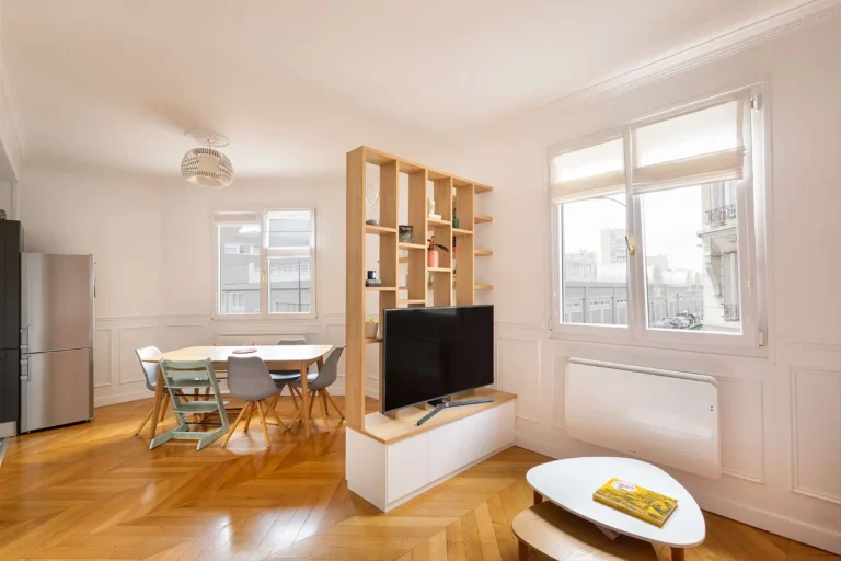 Bibliothèque claustra en bois clair sur mesure dans un salon haussmannien avec meuble bas intégré blanc mat