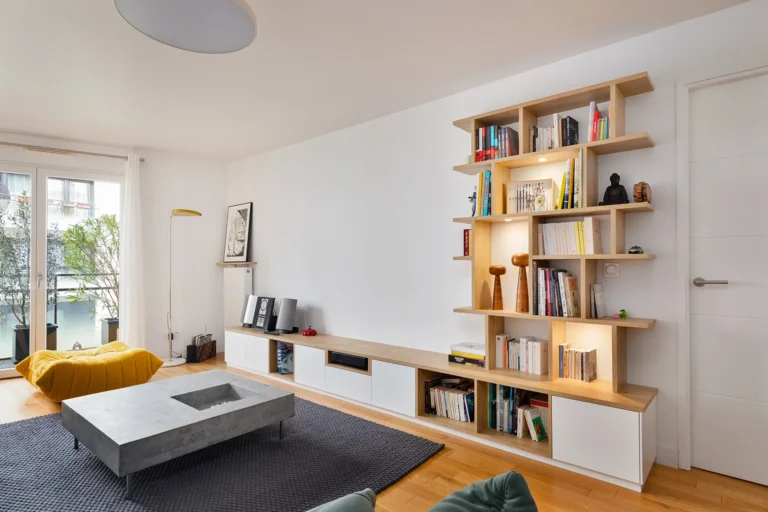 Bibliothèque meuble bas sur mesure dans un salon avec niches asymétriques en chêne clair et façades blanches