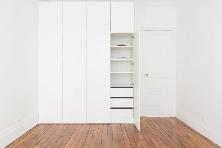 Vue d’ensemble d’un dressing blanc toute hauteur avec façades pleines sans poignées et finition laquée mate