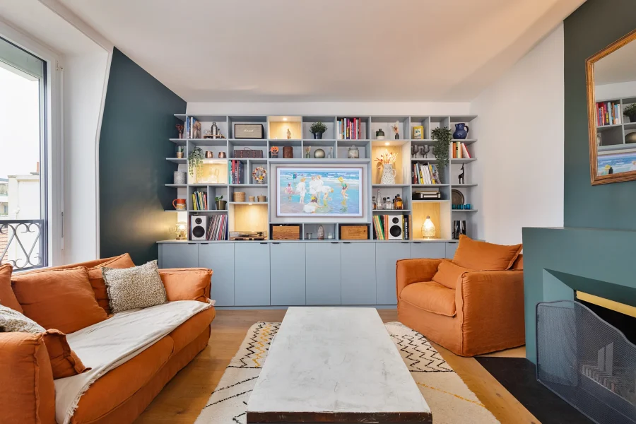 Agencement meuble TV sur mesure sous pente avec meuble bas bleu clair et niches en chêne clair