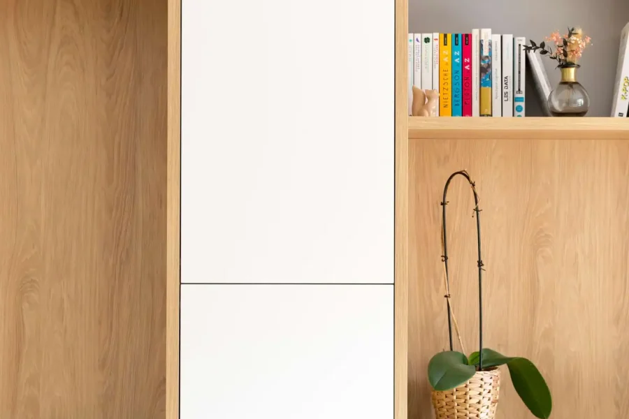 Vue d’ensemble d’une bibliothèque murale avec banquette intégrée, finition laqué blanc mat et mélaminé chêne clair