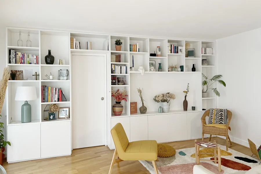 Bibliothèque laquée blanche sur mesure intégrée autour d’une porte, vue d’ensemble dans un salon contemporain