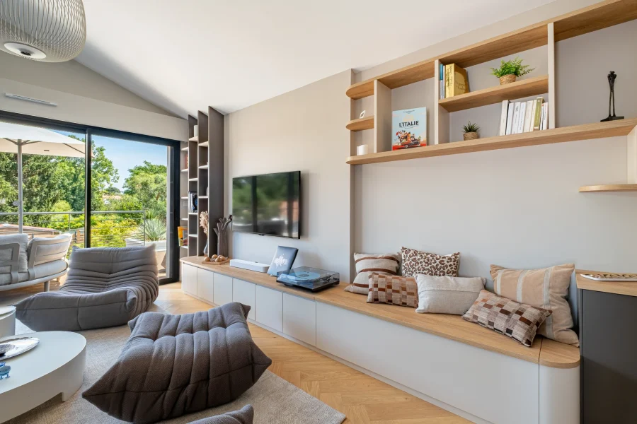 Banquette intégrée à une bibliothèque sur mesure avec rangements fermés, niches ouvertes et finitions contemporaines