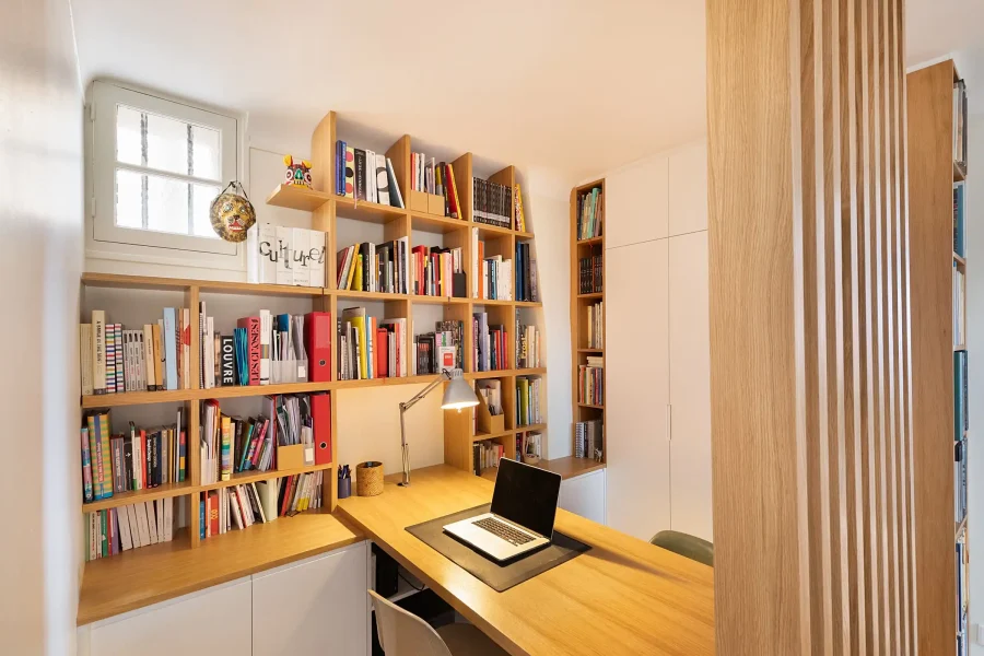 Bibliothèque sur mesure intégrée à un bureau cloisonné par un claustra en bois clair.