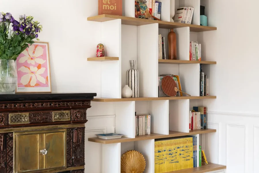 Bibliothèque sur mesure avec rangement bas discret, épousant une cheminée en pierre