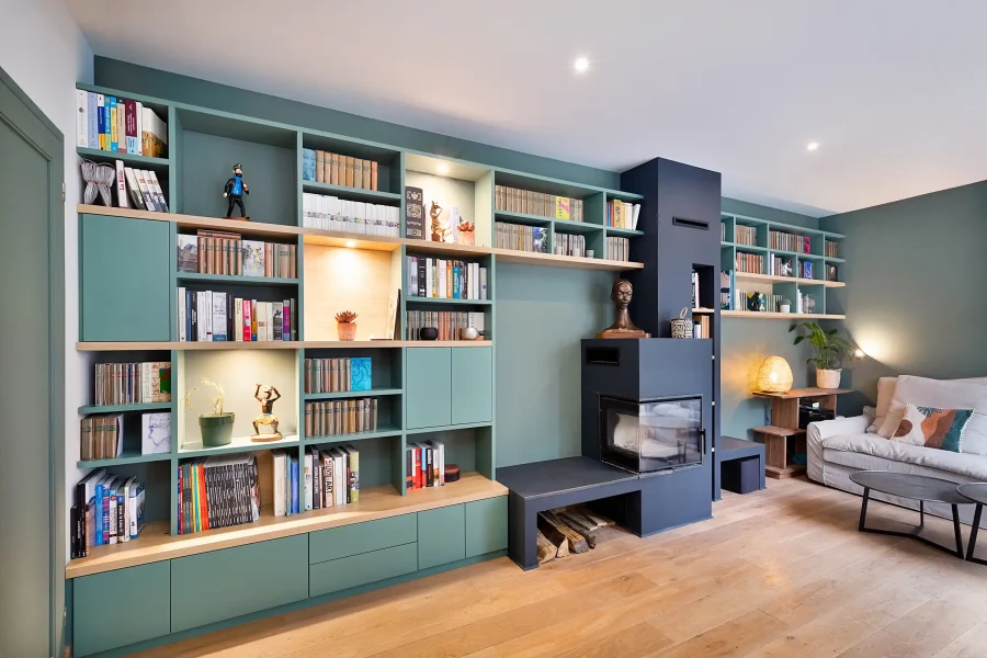 Vue d’ensemble d’une bibliothèque toute hauteur avec rangements fermés et éclairage intégré