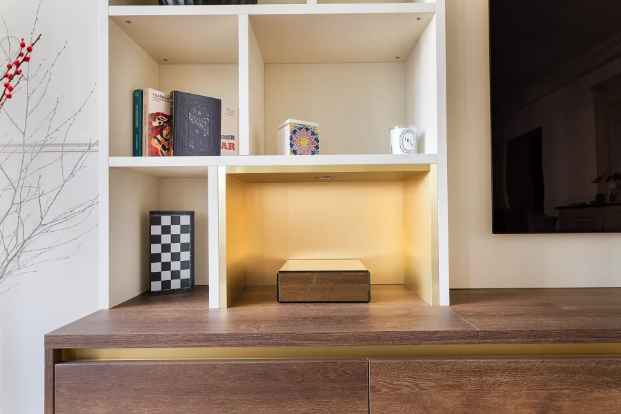 Détail d’une niche laquée avec éclairage LED et fond doré, posée sur meuble bas en bois naturel
