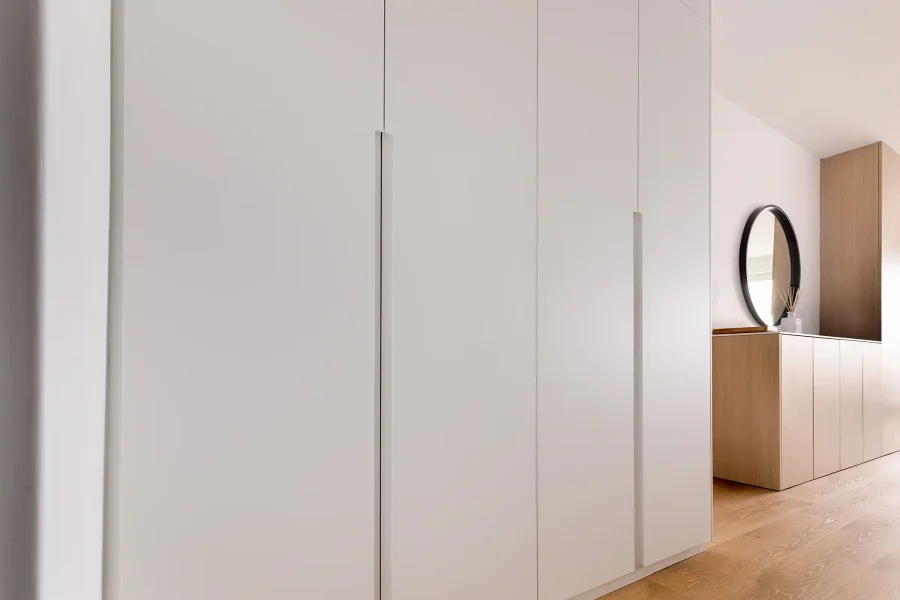 Détail des portes battantes blanches avec poignées invisibles et finition mate