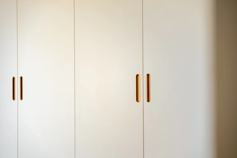 Façades laquées beige clair d’un dressing sur mesure avec poignées encastrées finition laiton