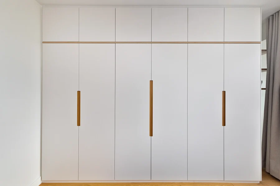 Dressing fermé à portes battantes avec poignées discrètes en bois clair