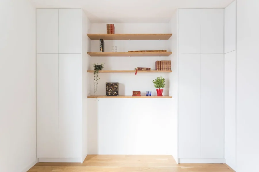 Vue d’ensemble d’un dressing sur mesure avec façades blanches sans poignées et étagères en chêne massif
