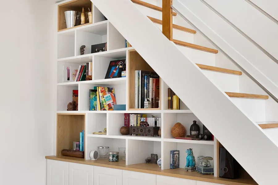 Étagères asymétriques en partie basse d’escalier avec portes blanches