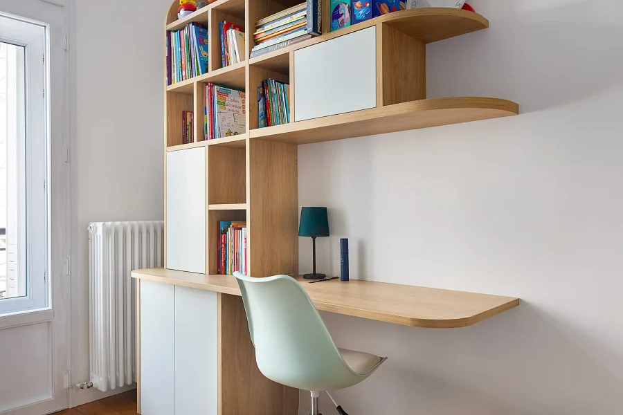 Meuble bureau avec bibliothèque intégrée dans une chambre d’enfant, finition bois clair et façades pastel
