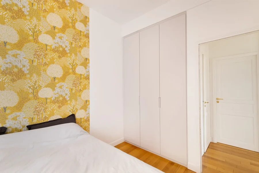 Meuble de rangement minimaliste sur mesure parfaitement ajusté entre murs et plafond dans une chambre