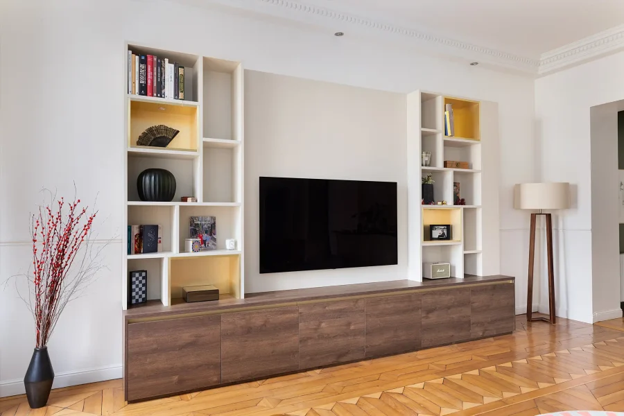 Intégration élégante d’un meuble TV traversant avec finitions bois et laque mate dans une pièce à moulures