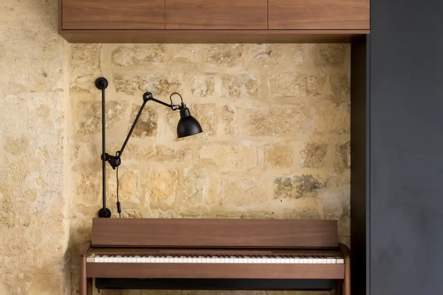 Détail du piano droit intégré sous un meuble suspendu en noyer