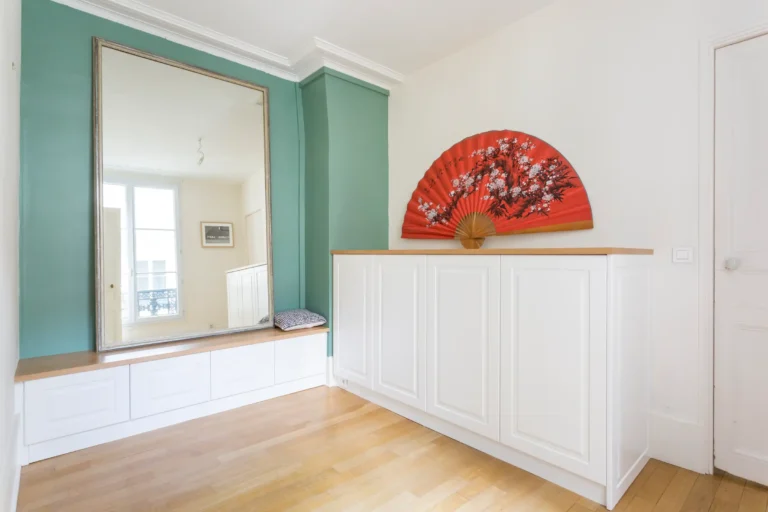 Meuble bas blanc avec plateau en chêne clair et façades à moulures dans un appartement parisien
