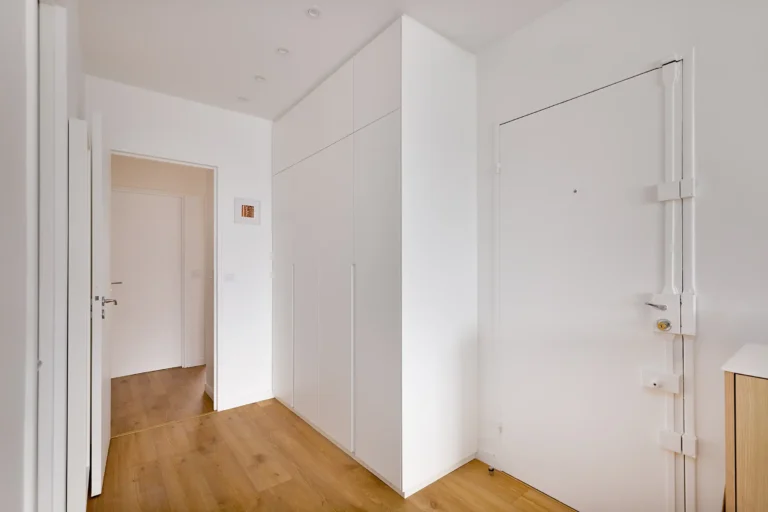 Vue frontale du vestiaire d’entrée sur mesure toute hauteur avec portes battantes blanches sans poignées